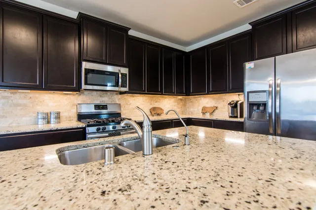 a kitchen with granite countertop a stove a sink and a microwave