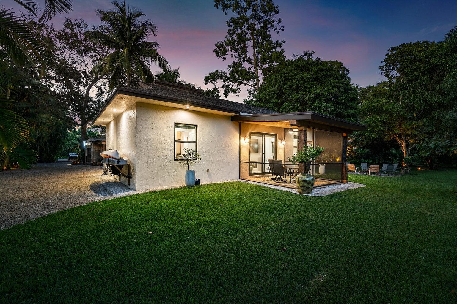 12466 Quercus Lane, Unit GUEST HOUSE Wellington, FL 33414 - Photo 18 of 24 a view of a backyard with table and chairs and potted plants and large tree