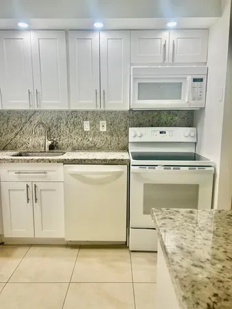 a kitchen with granite countertop white cabinets and white appliances