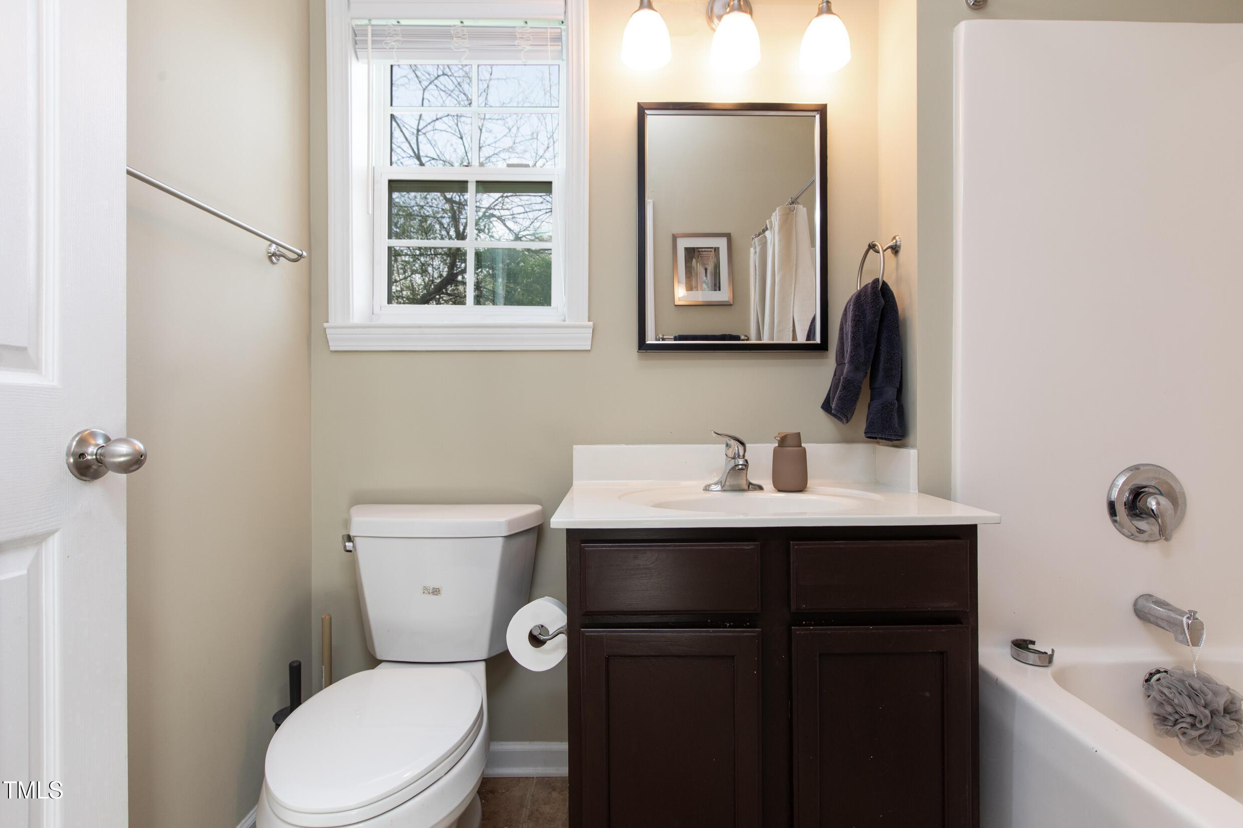 1208 Wall Street Durham, NC 27701 - Photo 14 of 16 a bathroom with a toilet a sink a mirror a window and vanity