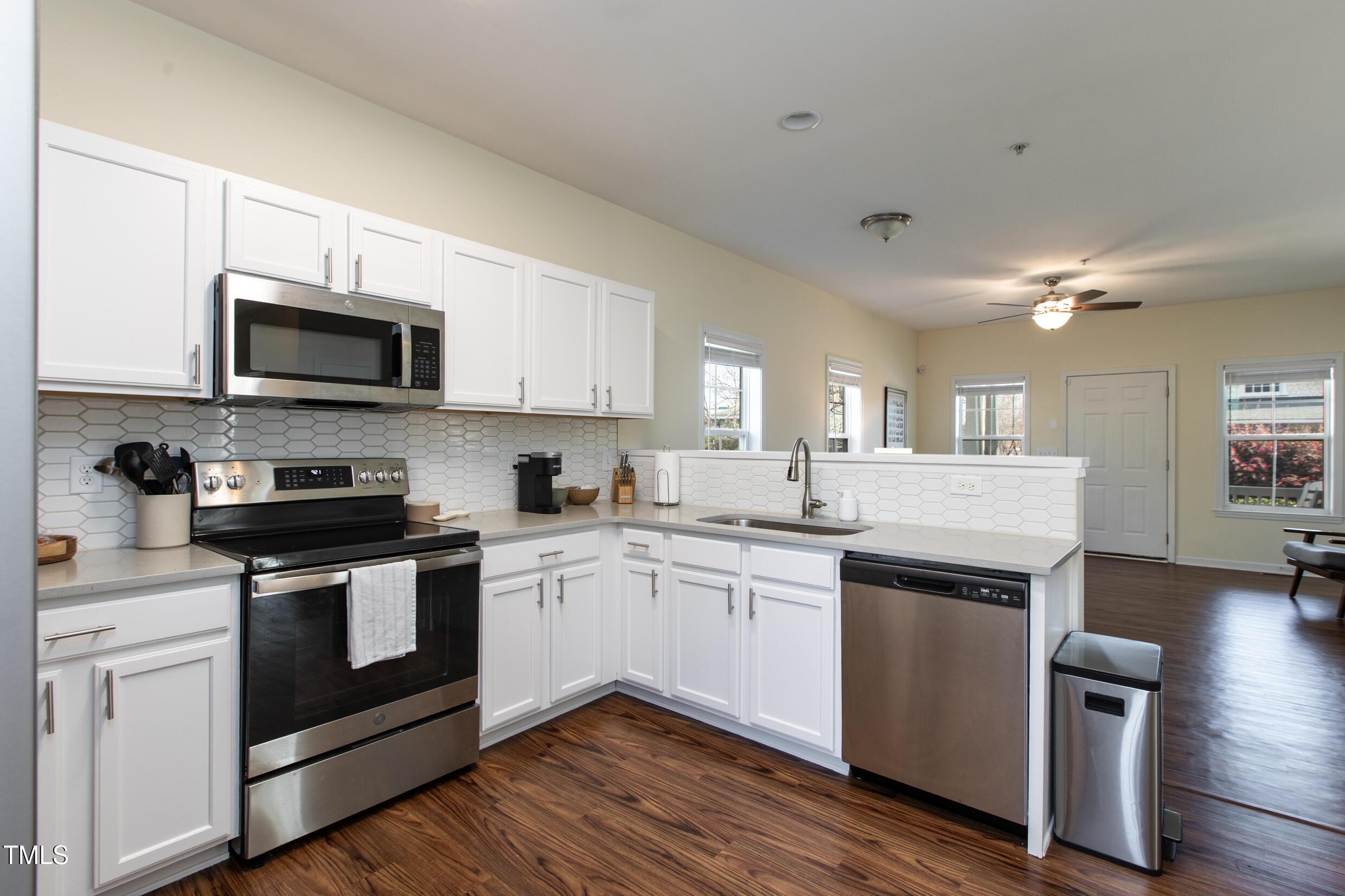 1208 Wall Street Durham, NC 27701 - Photo 7 of 16 a kitchen with stainless steel appliances granite countertop a stove top oven a sink dishwasher a refrigerator and white cabinets with wooden floor