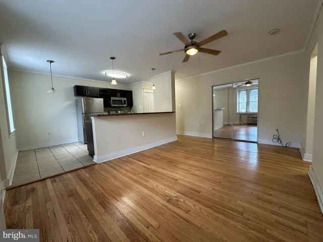 a view of empty room with wooden floor and kitchen view
