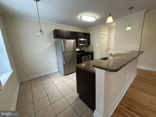 a kitchen with kitchen island granite countertop a sink a counter space and stainless steel appliances