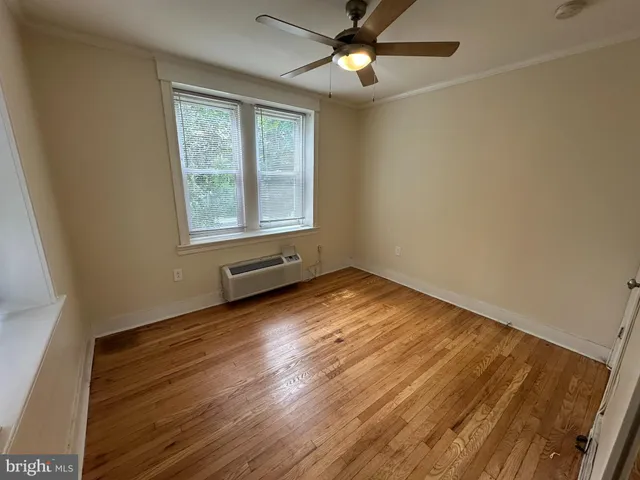 an empty room with wooden floor fan and windows