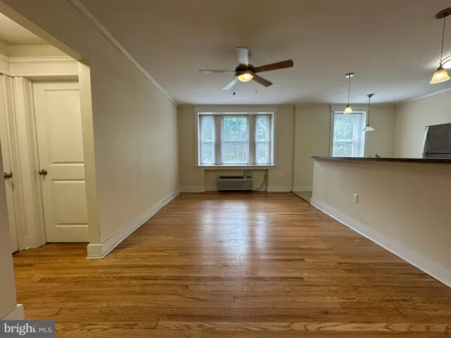 a view of empty room with wooden floor and fan