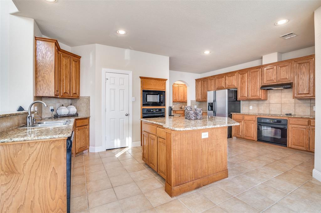 1113 Waterford Way Allen, TX 75013 - Photo 10 of 36 a large kitchen with stainless steel appliances granite countertop a stove refrigerator sink and cabinets
