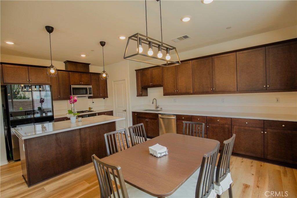 8529 Exposition Street Chino, CA 91708 - Photo 8 of 42 a kitchen with stainless steel appliances granite countertop a kitchen island a stove a table and chairs