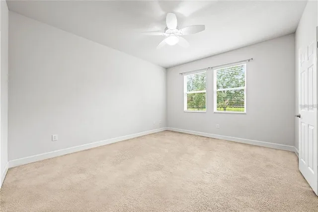 an empty room with a chandelier fan and windows