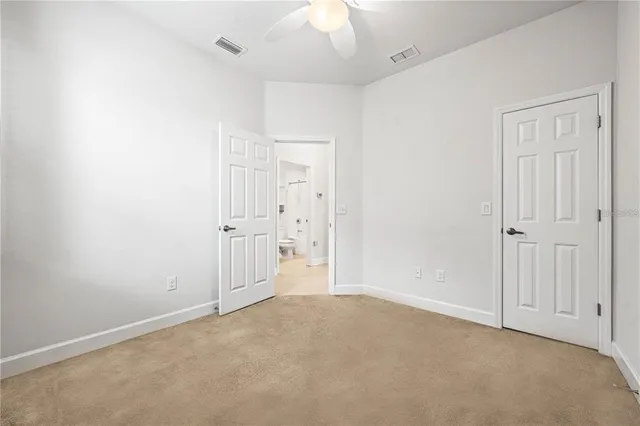 an empty room with a ceiling fan and bathroom view