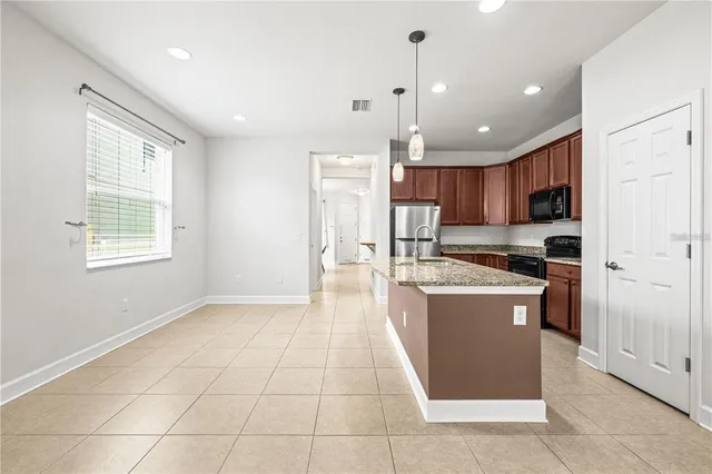 a kitchen with stainless steel appliances granite countertop a refrigerator a sink a stove top oven and a refrigerator