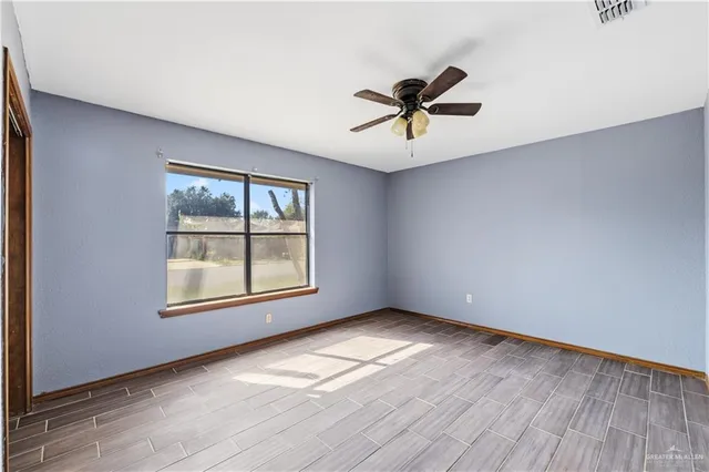 a view of empty room with wooden floor and fan