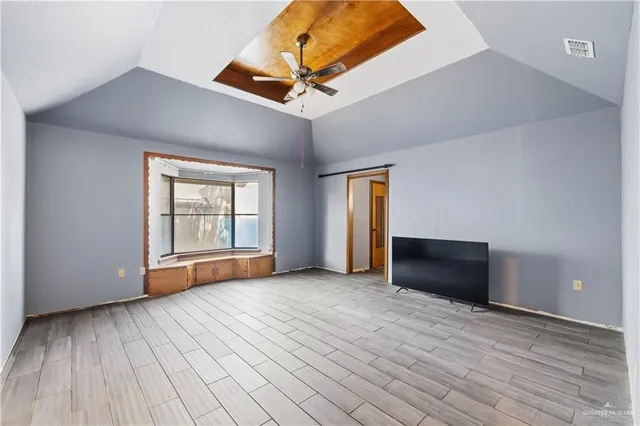 a view of empty room with wooden floor and fan