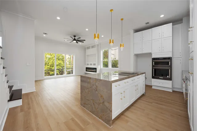 a large kitchen with stainless steel appliances granite countertop a stove a sink a refrigerator and a wooden floor