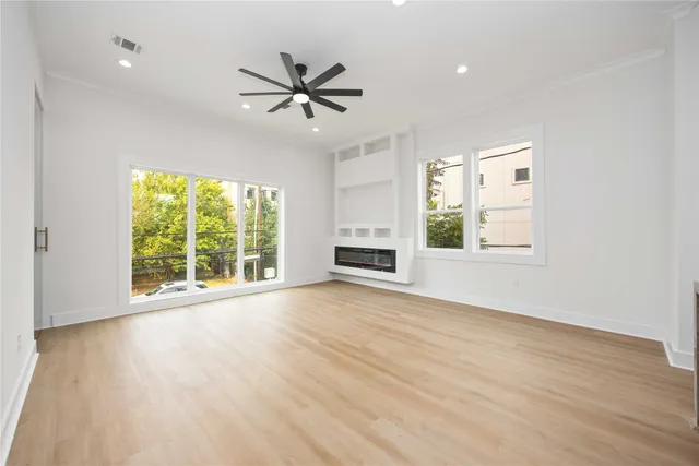 a view of an empty room with a window and wooden floor