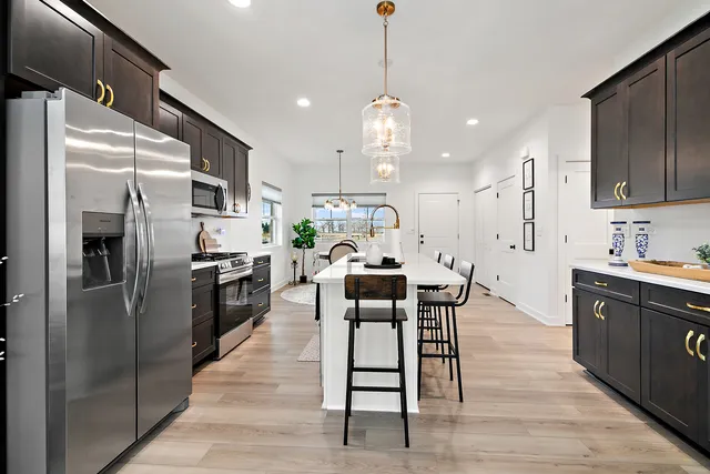 a large kitchen with stainless steel appliances kitchen island granite countertop a refrigerator a stove a sink a dining table and chairs with wooden floor