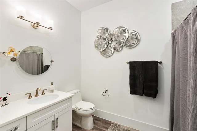 a bathroom with a toilet sink vanity and mirror