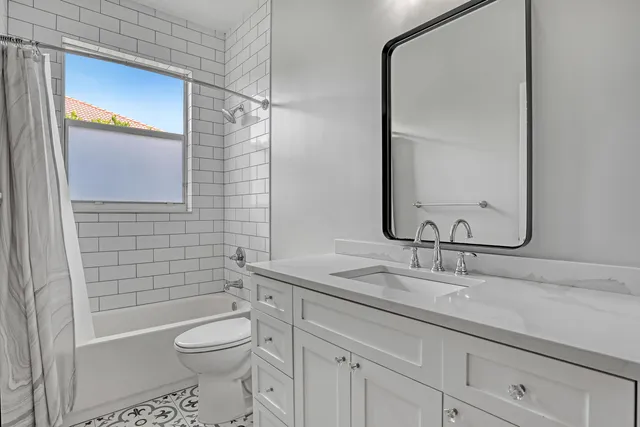 a bathroom with a granite countertop sink a toilet and shower