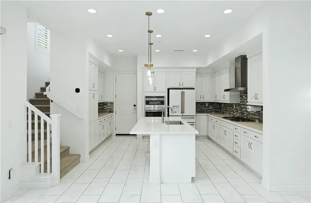 a kitchen with stainless steel appliances a counter space a sink and a refrigerator