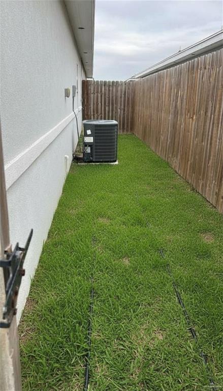 1809 Stauffer Street, Unit 4 Weslaco, TX 78596 - Photo 12 of 12 Side yard featuring a privacy fence, stucco siding, and a central air conditioning unit