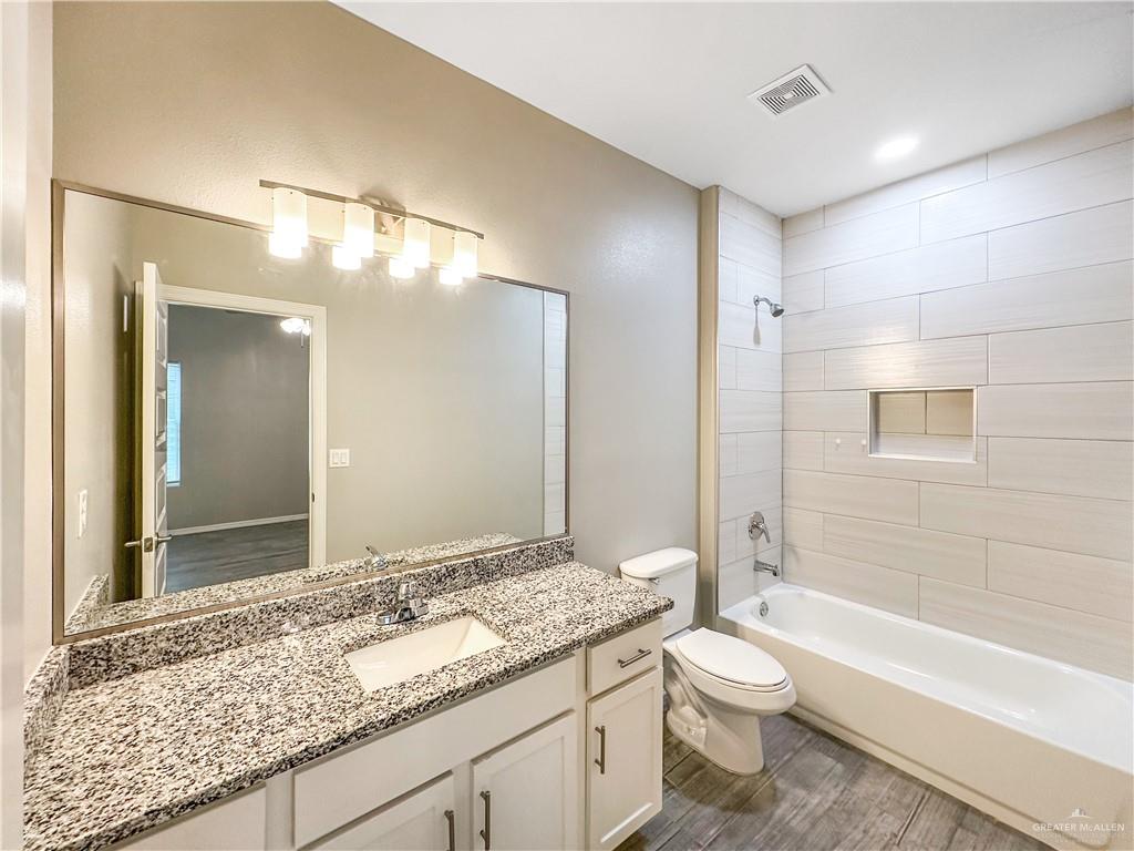 1809 Stauffer Street, Unit 4 Weslaco, TX 78596 - Photo 7 of 12 Bathroom featuring a single vanity with granite-style countertop, white cabinetry with dark pulls, full wall mirror, and a five-light fixture
