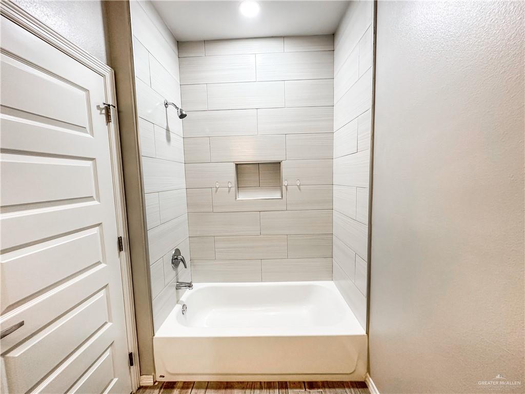 1809 Stauffer Street, Unit 4 Weslaco, TX 78596 - Photo 9 of 12 Bathtub and shower combination featuring light-toned horizontal tile work, a recessed shower niche, and chrome fixtures