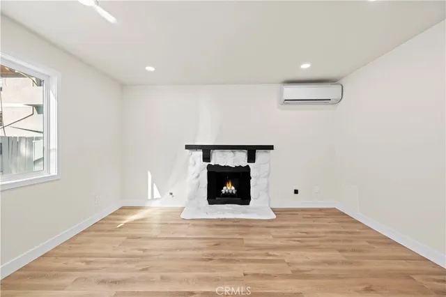 a view of an empty room with wooden floor fireplace and a window