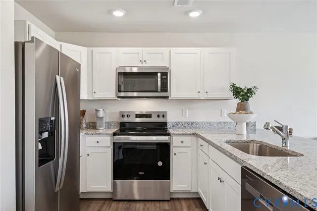 a kitchen with stainless steel appliances granite countertop a stove a refrigerator and a sink