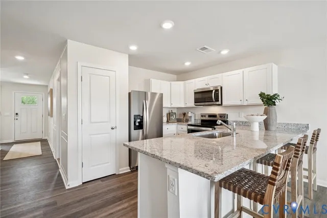 a kitchen with stainless steel appliances granite countertop a refrigerator a stove a microwave a sink and dishwasher with wooden floor