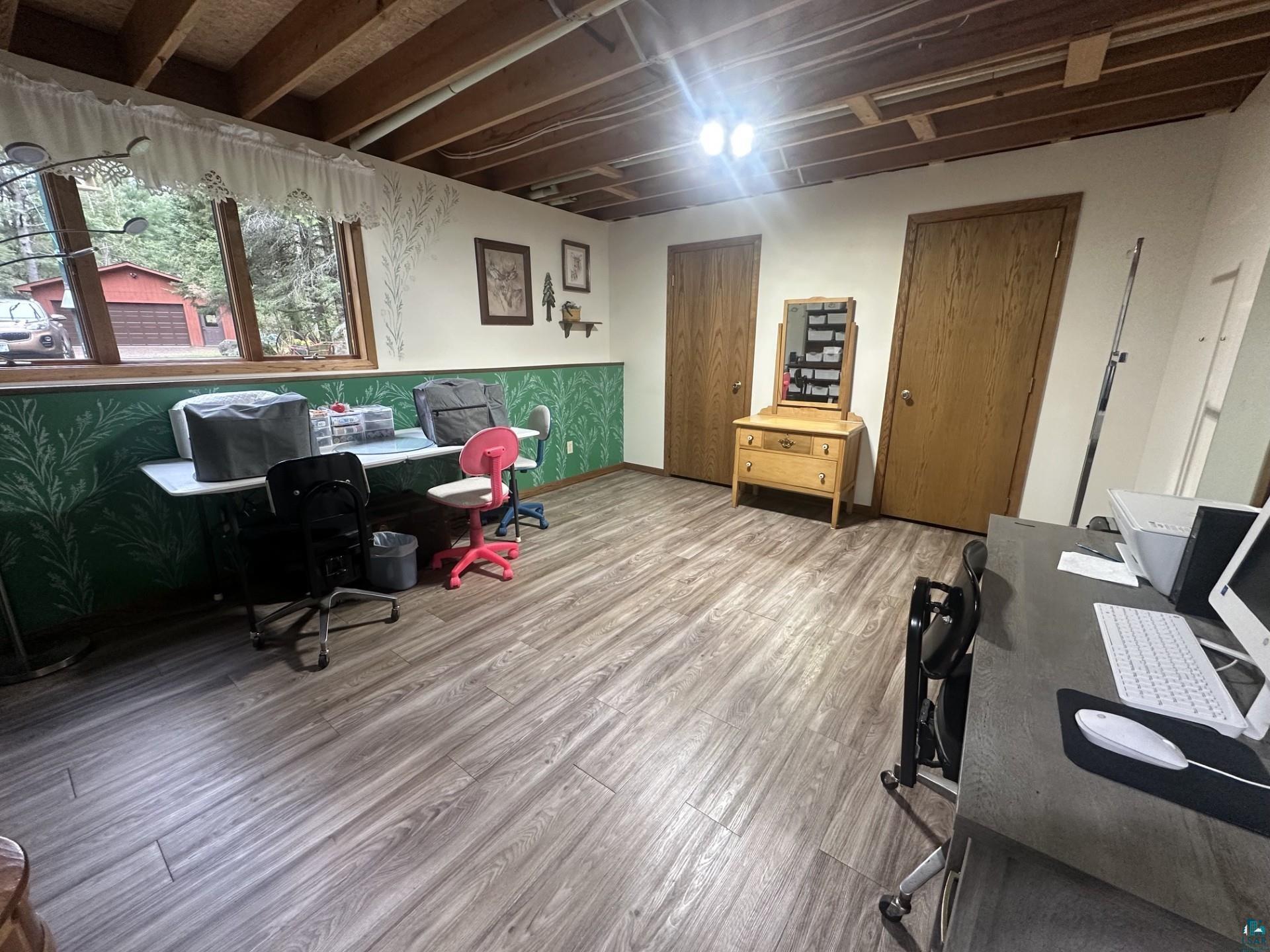 81 Hautaluoma Road Esko, MN 55733 - Photo 31 of 43 Spacious room featuring wood-finish flooring, exposed ceiling beams, multiple windows, and two interior doors