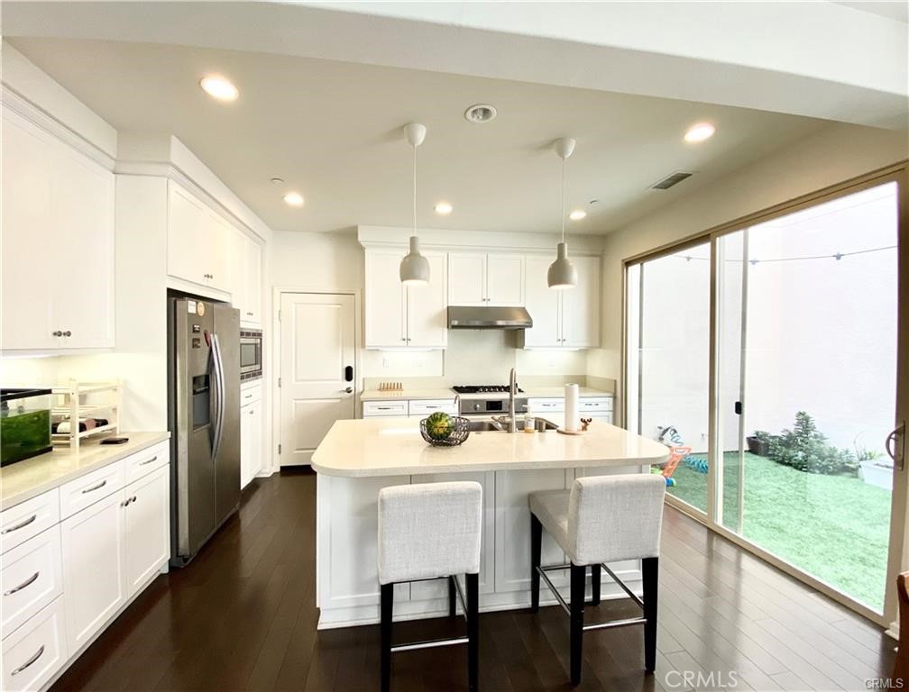 62 Emerald Clover Irvine, CA 92620 - Photo 5 of 15 a kitchen with stainless steel appliances kitchen island granite countertop a stove a refrigerator a sink a dining table and chairs with wooden floor