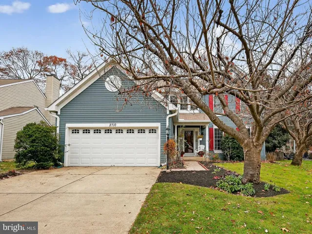 a front view of a house with a yard and an tree