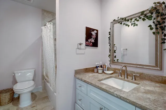 a bathroom with a granite countertop sink toilet and mirror