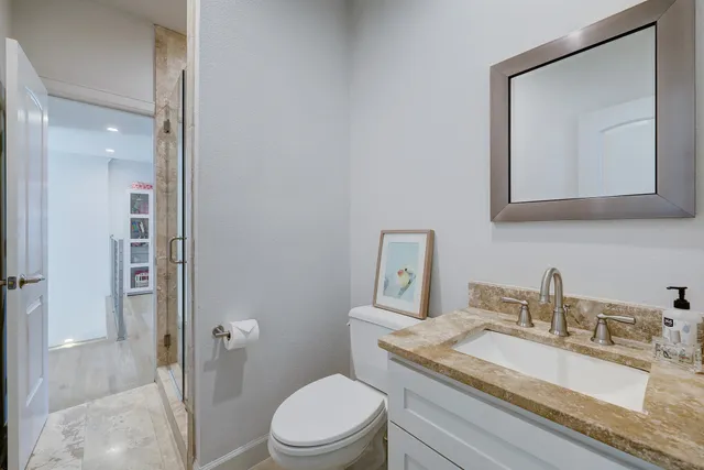 a bathroom with a granite countertop toilet sink and mirror