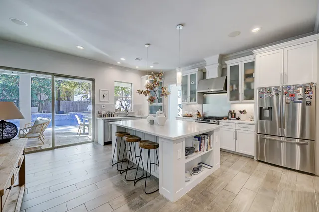 a kitchen with stainless steel appliances granite countertop a stove top oven a refrigerator a sink and a dining table with wooden floor