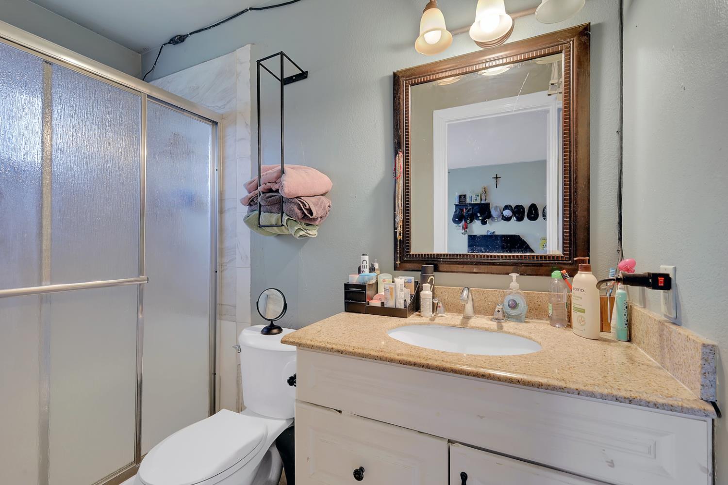 3132 4th Street Biggs, CA 95917 - Photo 15 of 21 a bathroom with a granite countertop sink a toilet and mirror