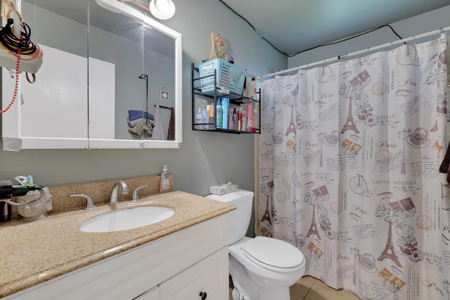 3132 4th Street Biggs, CA 95917 - Photo 16 of 21 a bathroom with a granite countertop sink a toilet and a shower curtain