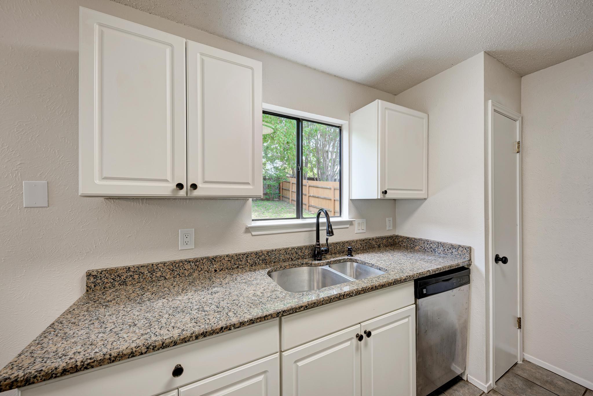 12108 Carnforth Drive Austin, TX 78753 - Photo 16 of 33 a kitchen with granite countertop white cabinets and a sink