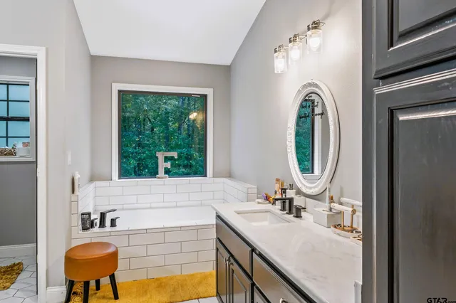 a bathroom with a granite countertop sink a mirror and a bathtub