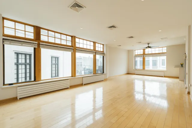 a view of an empty room with a window and kitchen area