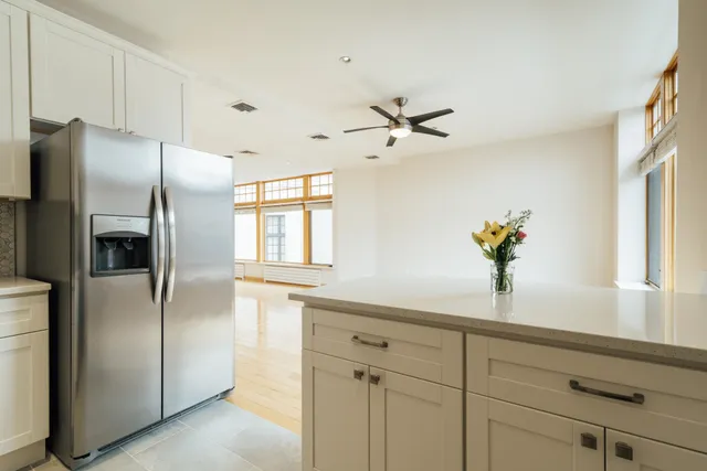 a kitchen with stainless steel appliances granite countertop a refrigerator a sink and white cabinets