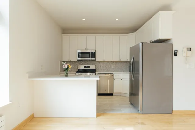 a kitchen with a refrigerator a stove top oven and white cabinets
