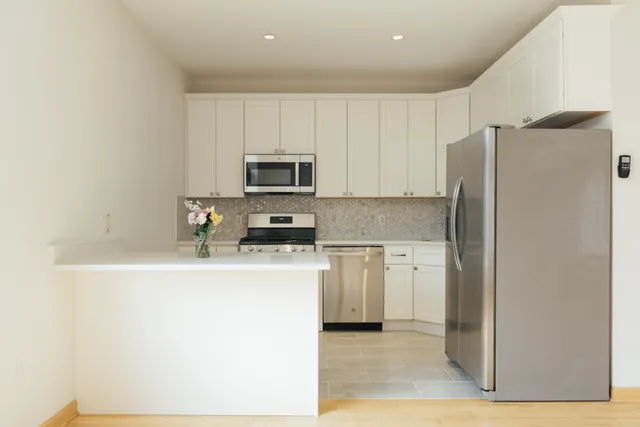 a kitchen with a refrigerator a stove top oven and white cabinets
