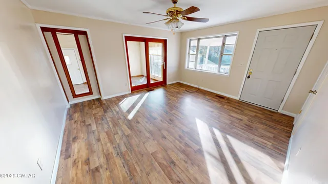 a view of empty room with wooden floor and fan