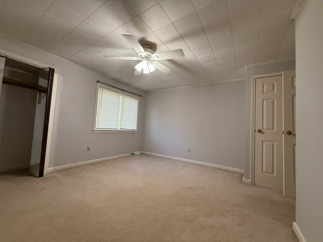 an empty room with chandelier fan and windows