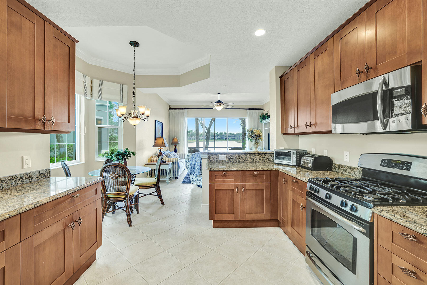 9234 Tesoro, Unit 101 Naples, FL 34114 - Photo 11 of 25 a kitchen with stainless steel appliances granite countertop a stove top oven a sink dishwasher a dining table and chairs with wooden floor