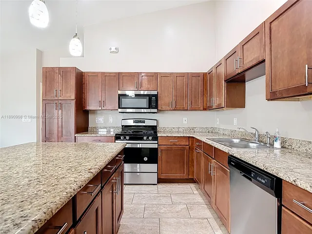 a kitchen with stainless steel appliances granite countertop a sink stove microwave and refrigerator