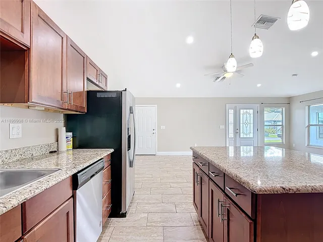 a kitchen with granite countertop kitchen island a sink appliances and cabinets