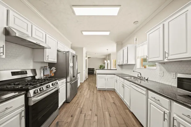 a kitchen with stainless steel appliances a sink cabinets and wooden floor