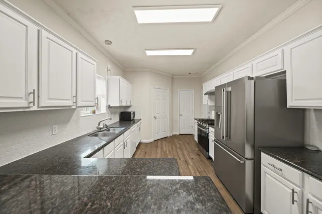 a kitchen with granite countertop a refrigerator sink and cabinets