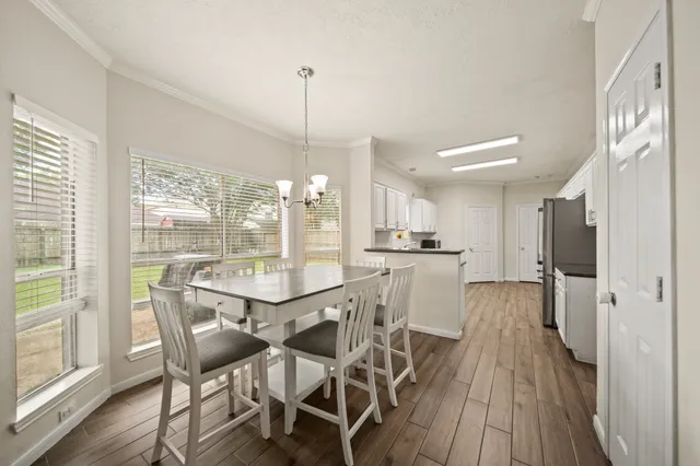 a dining area with furniture a chandelier and wooden floor